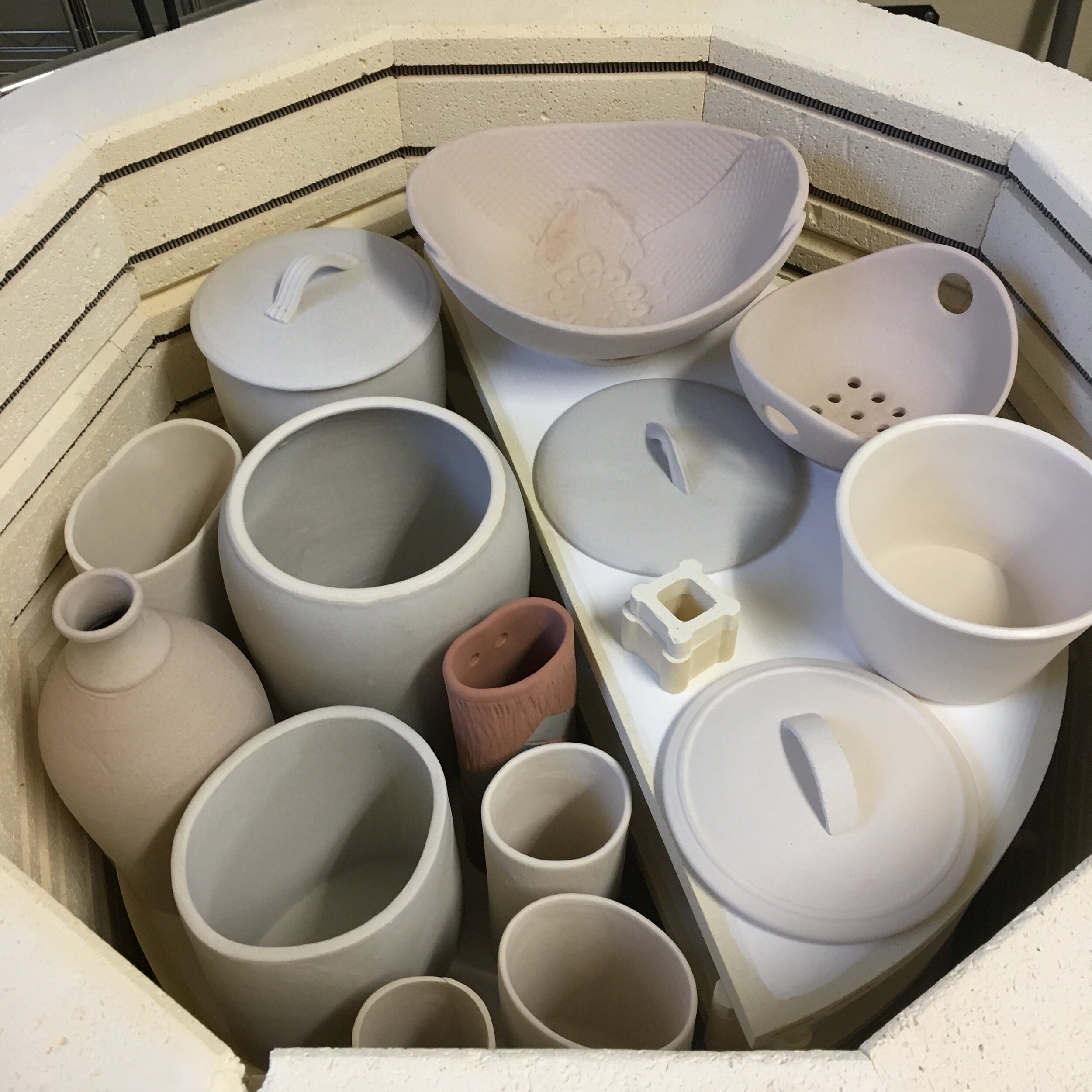 Top shelf in kiln loaded with pots.