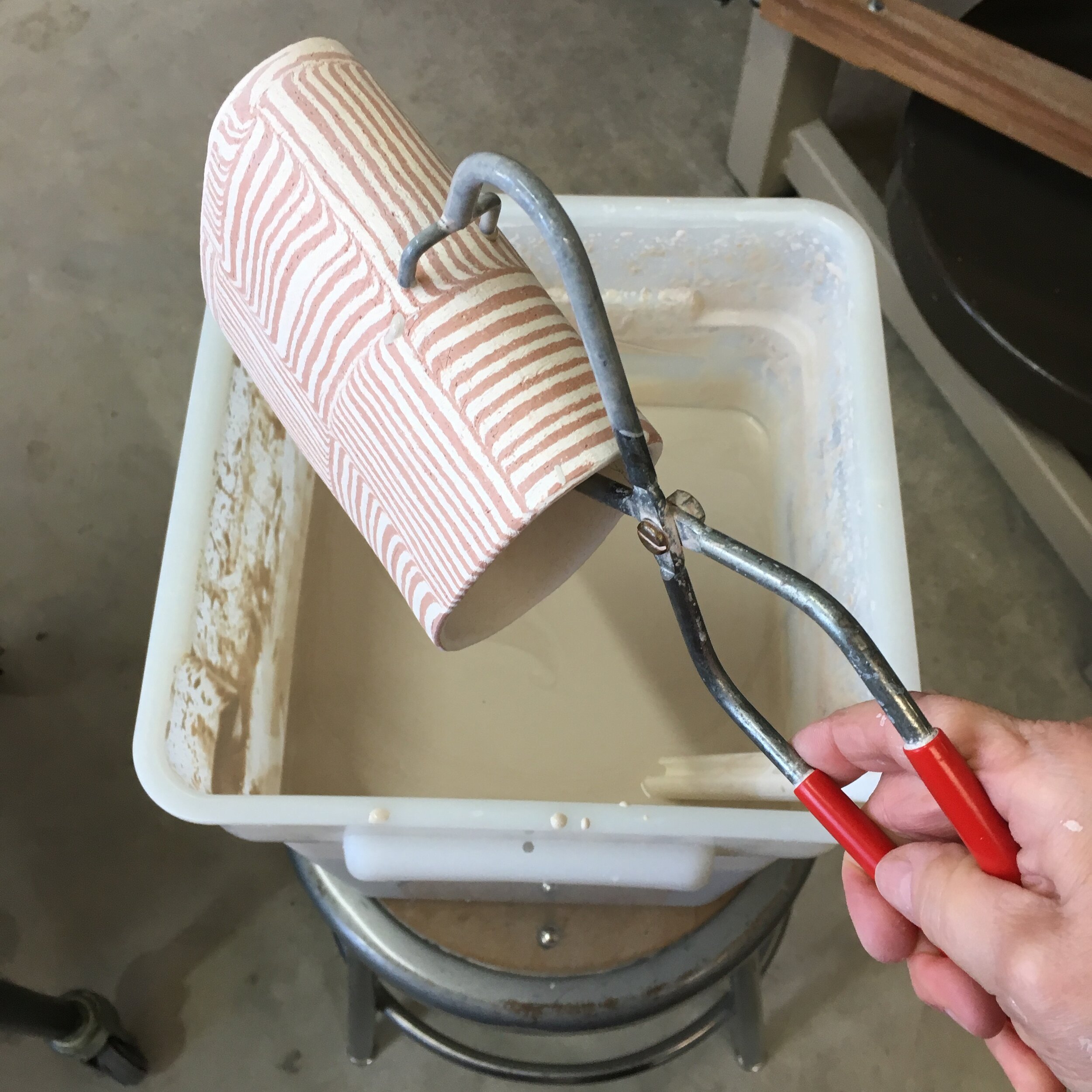 Pot being lowered into the dipping glaze.