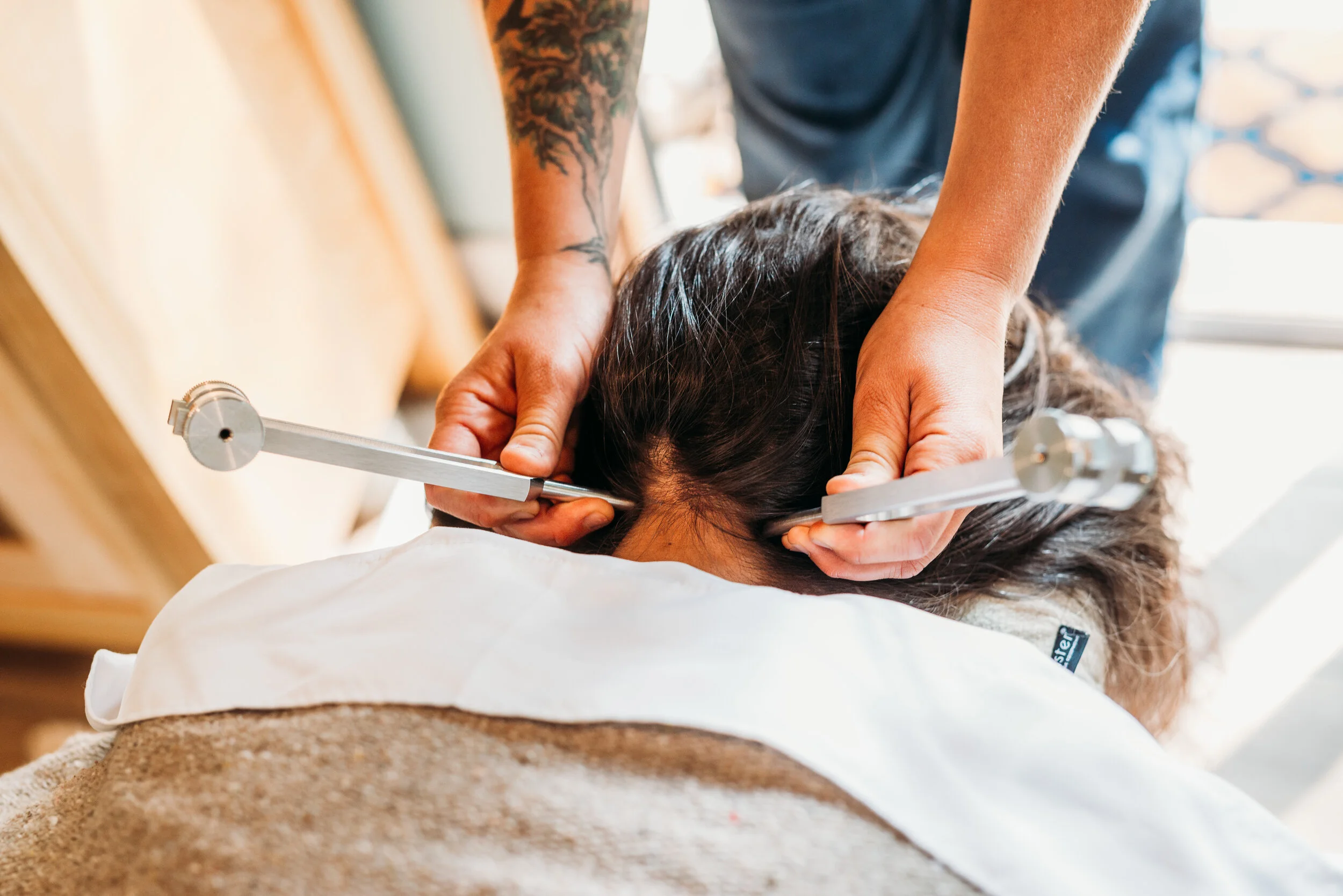 Chiropractor performing an adjustment on a patient's neck using a specialized tool.
