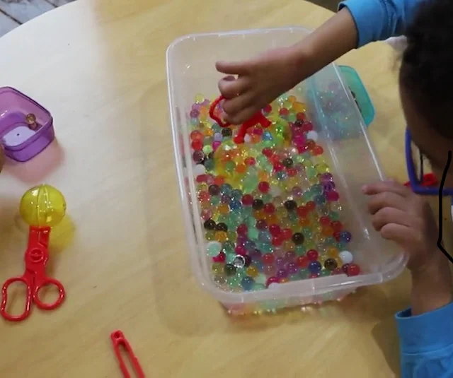 An example of a child playing with Li’l Gen Water Bead to develop pre-scissor skills.