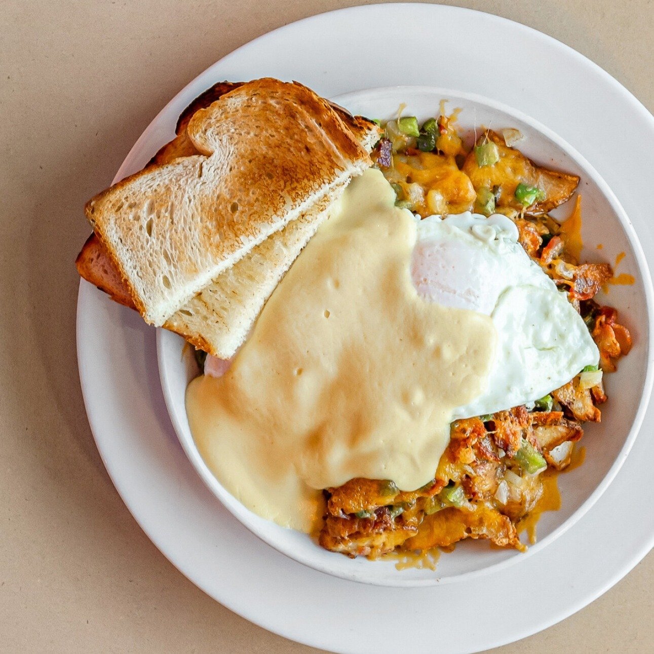 The perfect breakfast to start your day is our Roadside Skillet 😍 Two eggs your way served on top of homies, onions, peppers, bacon, cheddar cheese, topped with hollandaise sauce &amp; served with a side of toast