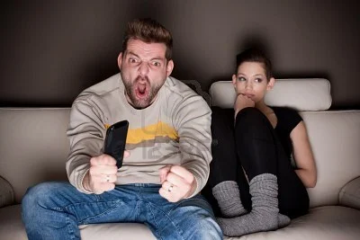 9687914-goaaaaal-a-man-watching-football-while-his-girlfriend-is-sitting-besides-him-bored-showing-the-diffe.jpg