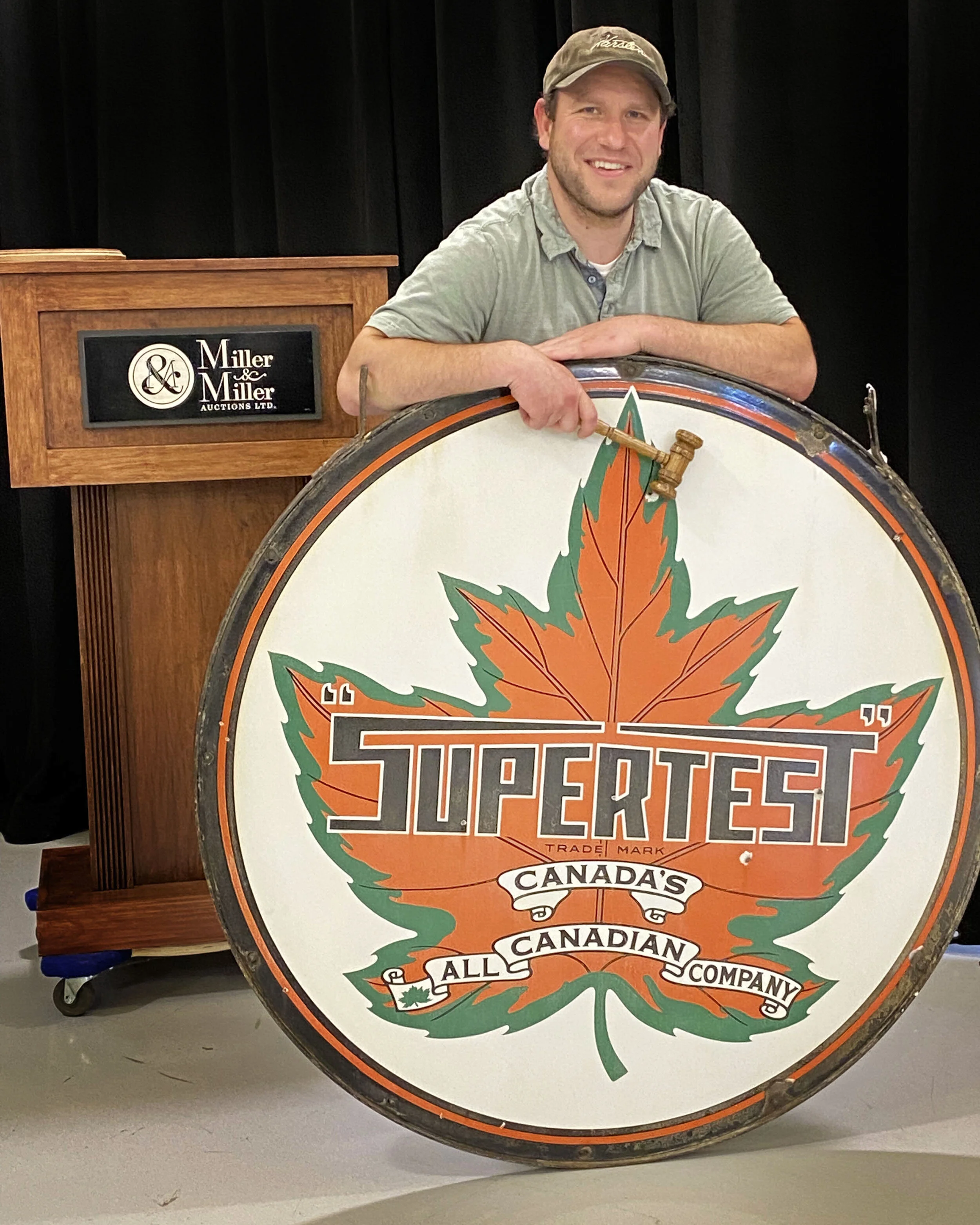 Justin Miller poses with the Supertest 4' Porcelain Service Station Sign which brought $20,060 at the May 15th sale of Petroliana &amp; Advertising.