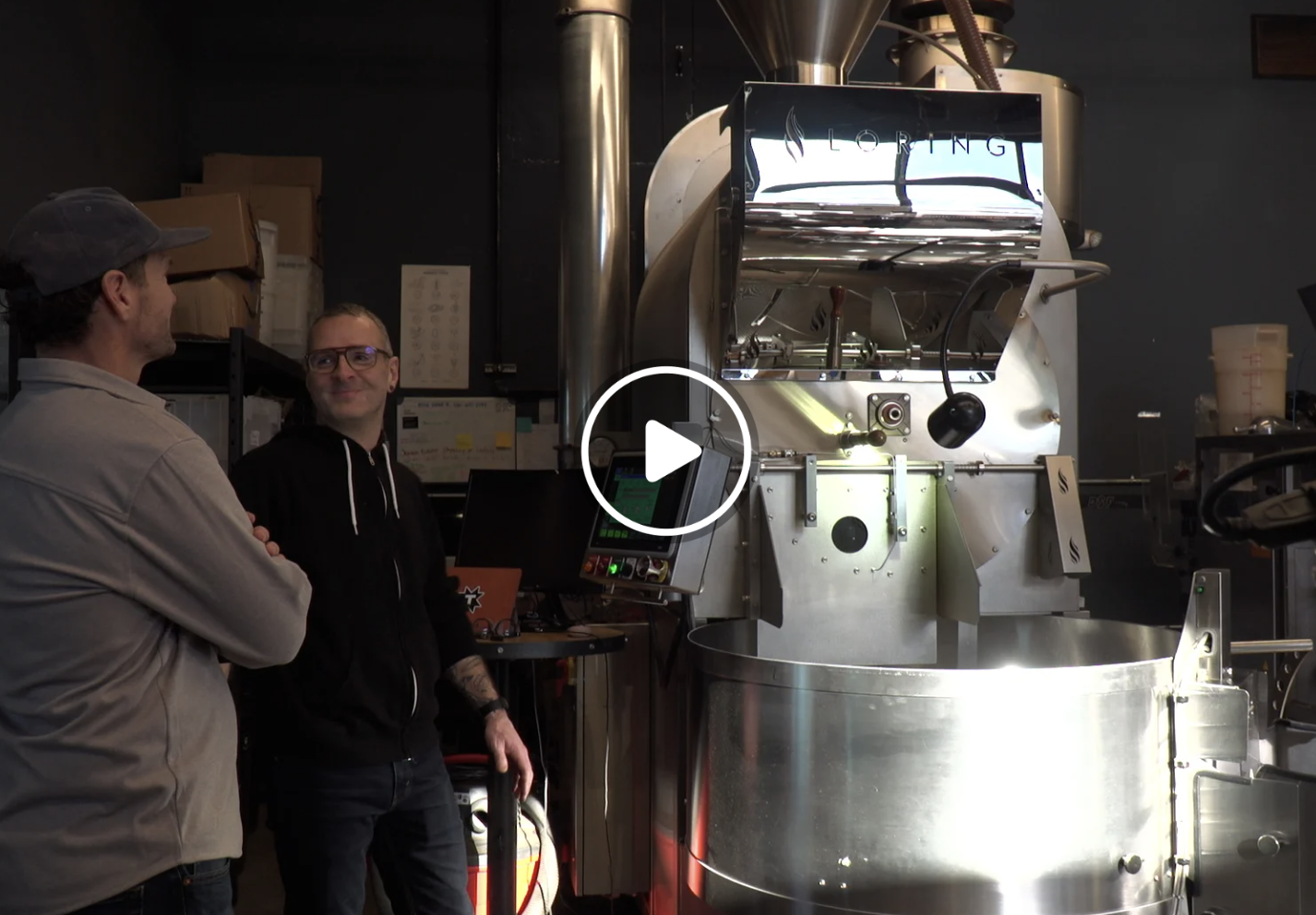 Bobby and Dave standing and talking near Thump coffee roasting machine in a coffee roasting facility.