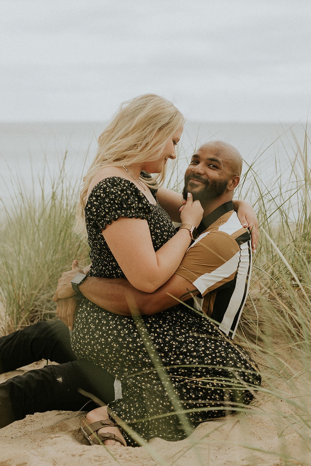  woman kneeling on man on the beach at Grand Haven Engagement session 