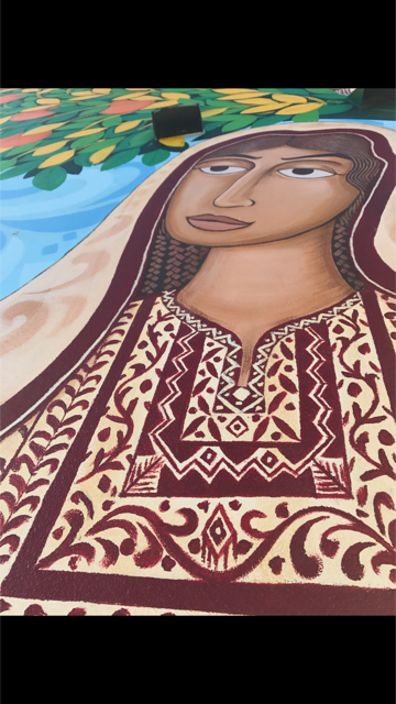 Part of Amals Tateez (Palestinian embroidery). The design is not from a specific region but inspired by multiple areas in Palestine, though the colors in her dress resemble the Ramallah region.