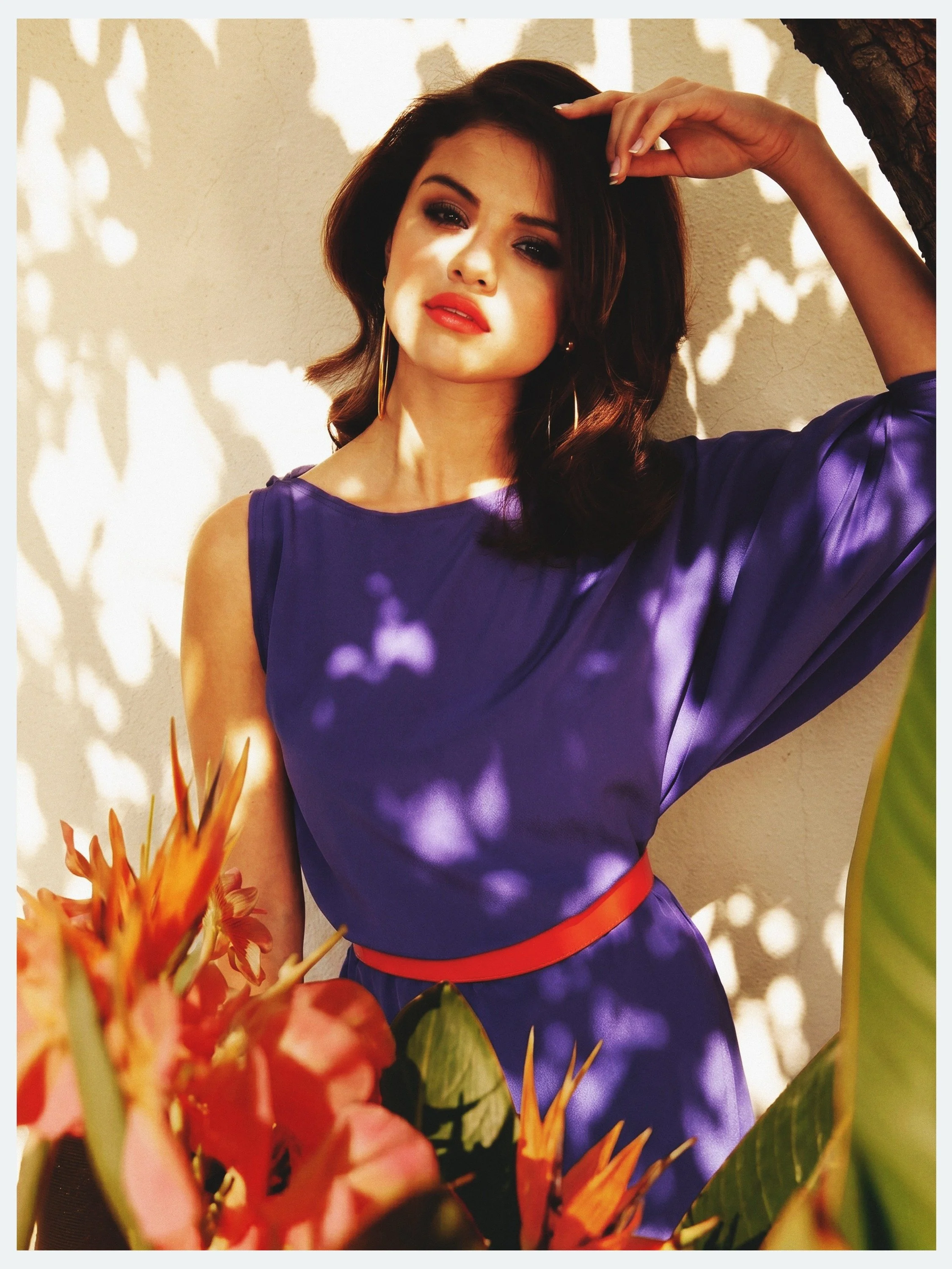 Selena Gomez in a violet dress with leaf shadows and tropical flowers for Elle México, by celebrity photographer Steven Gomillion