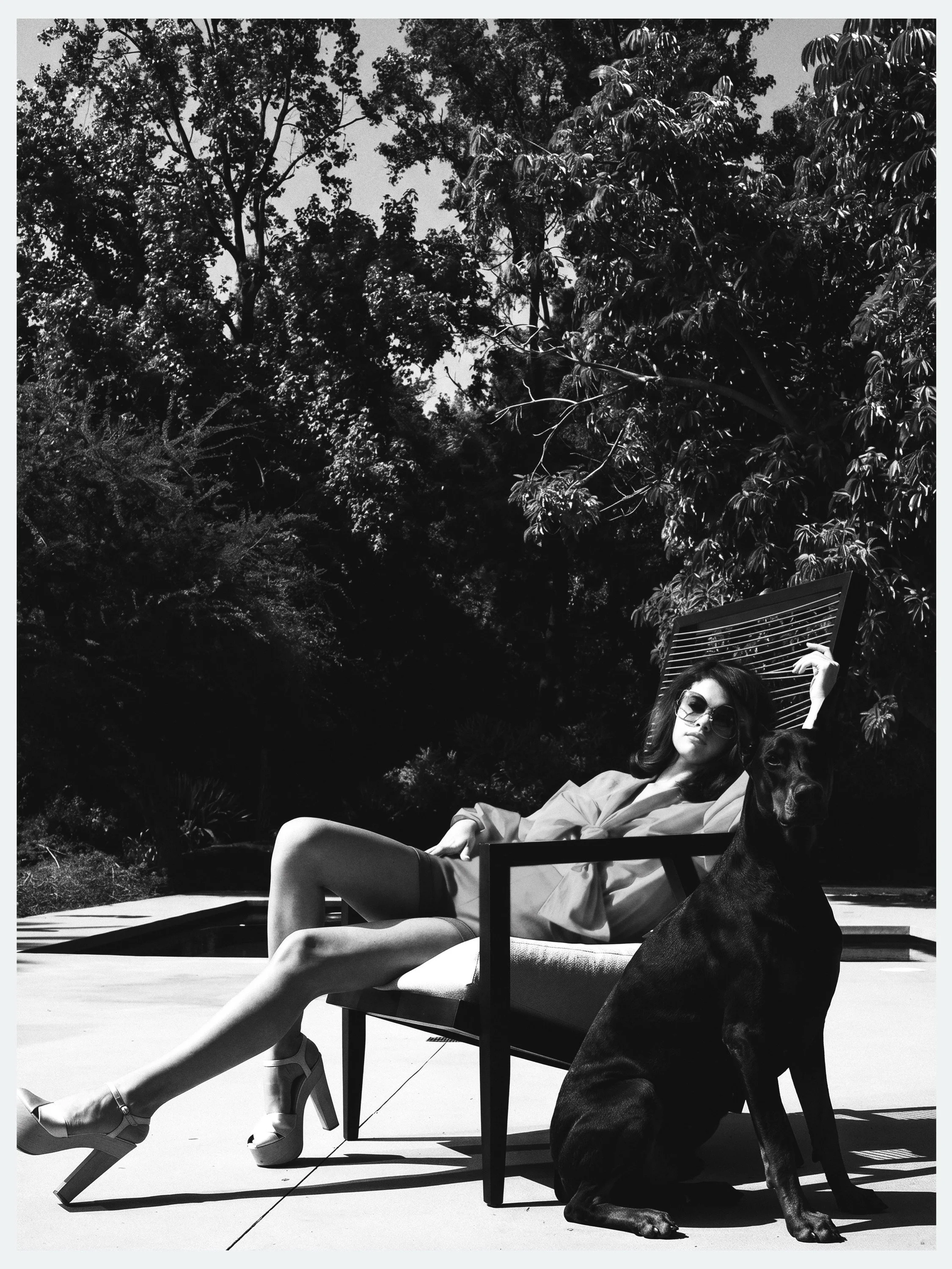 Selena Gomez lounging poolside with a Doberman in black and white for Elle México, by celebrity photographer Steven Gomillion