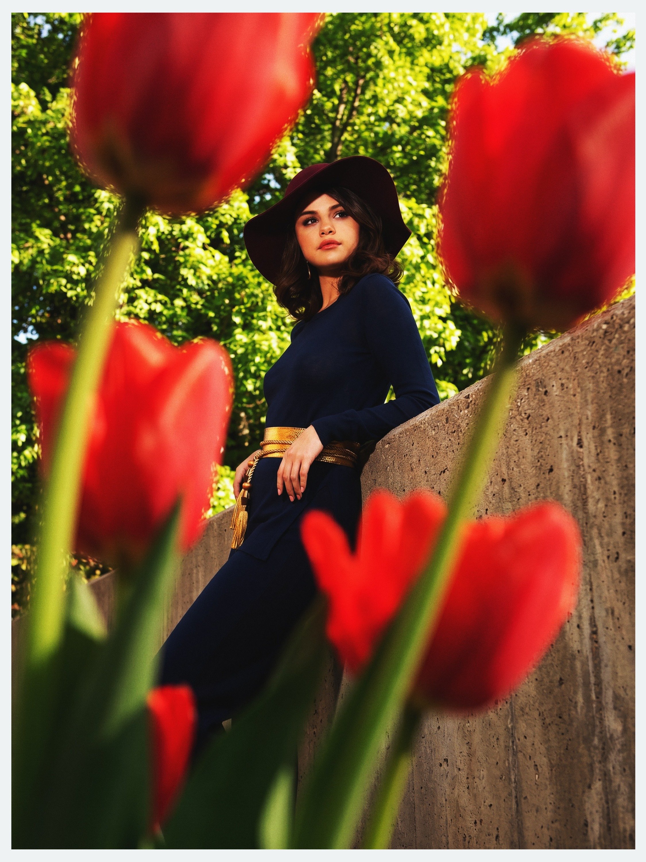 Selena Gomez in a wide-brim hat behind red tulips for her Elle México cover story by celebrity photographer Steven Gomillion