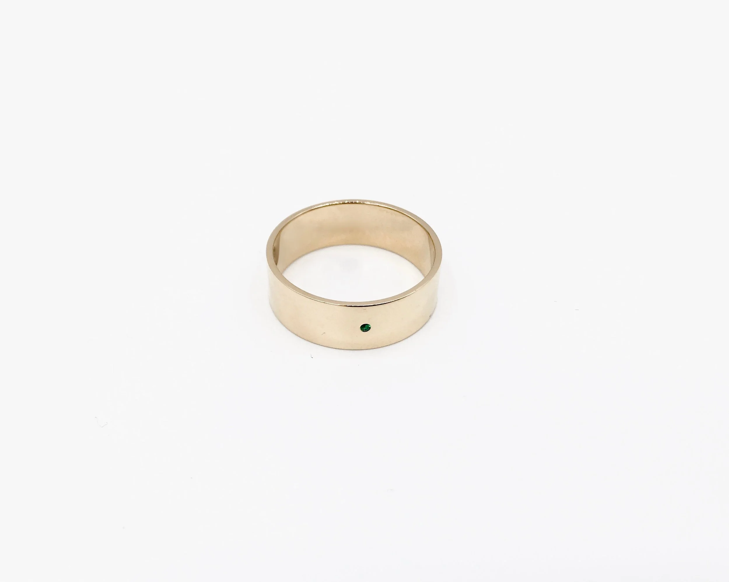 Custom 14k gold band with single emerald