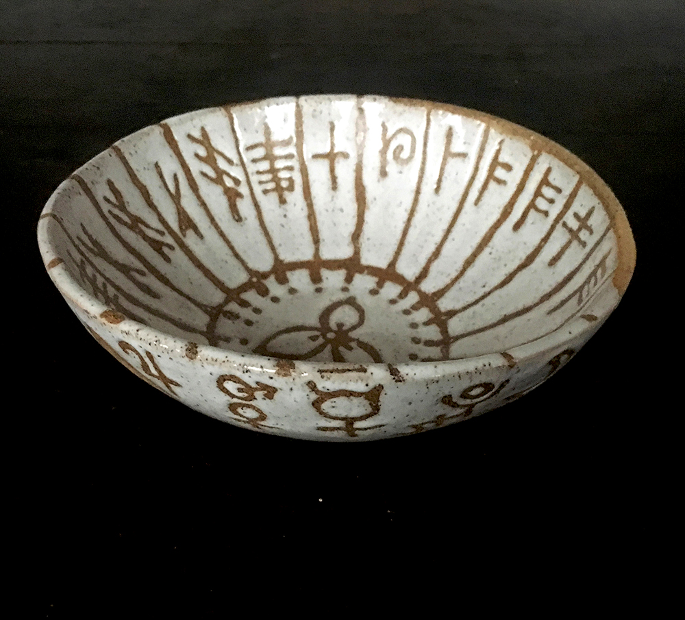  medium bowl with 20 letters of the  ogham  alphabet on inside and symbols  encircling outside in white on speckled clay 