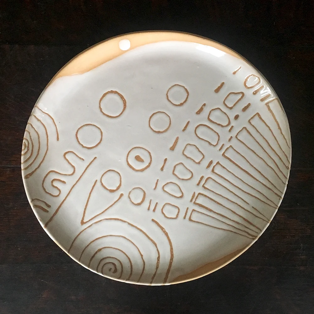 charger with elements of neolithic sundial on a rock in ireland: white on blush clay