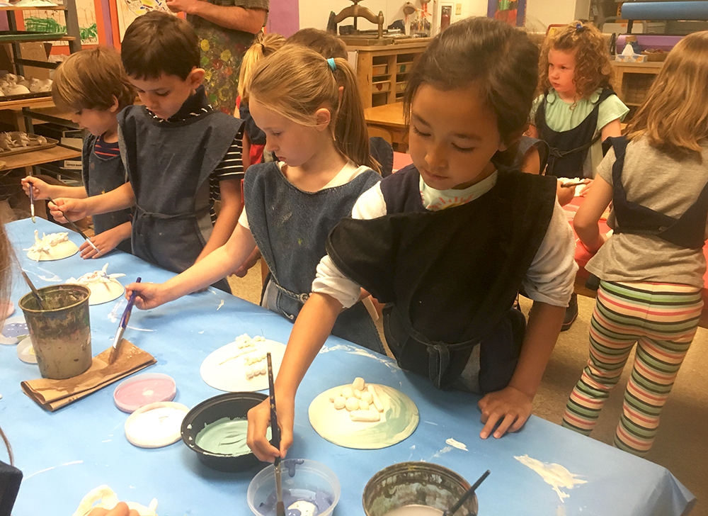 Students painting ceramic color on bisqued shields and sculpture.
