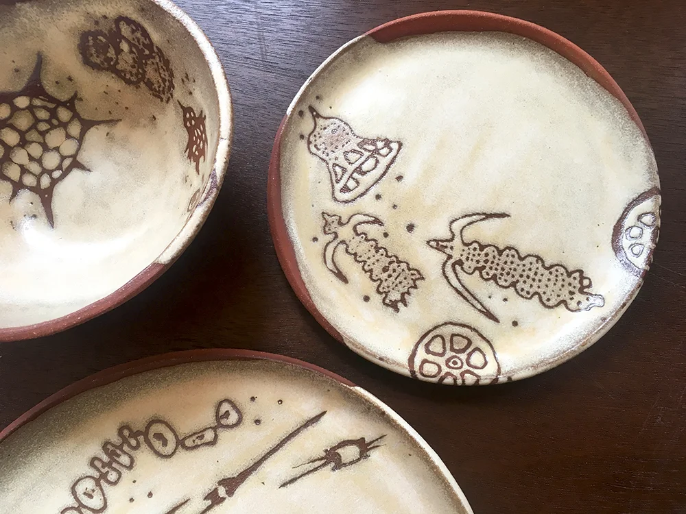 Detail of place setting with small bowl, 7” & dinner plate in créme brûlée on red clay