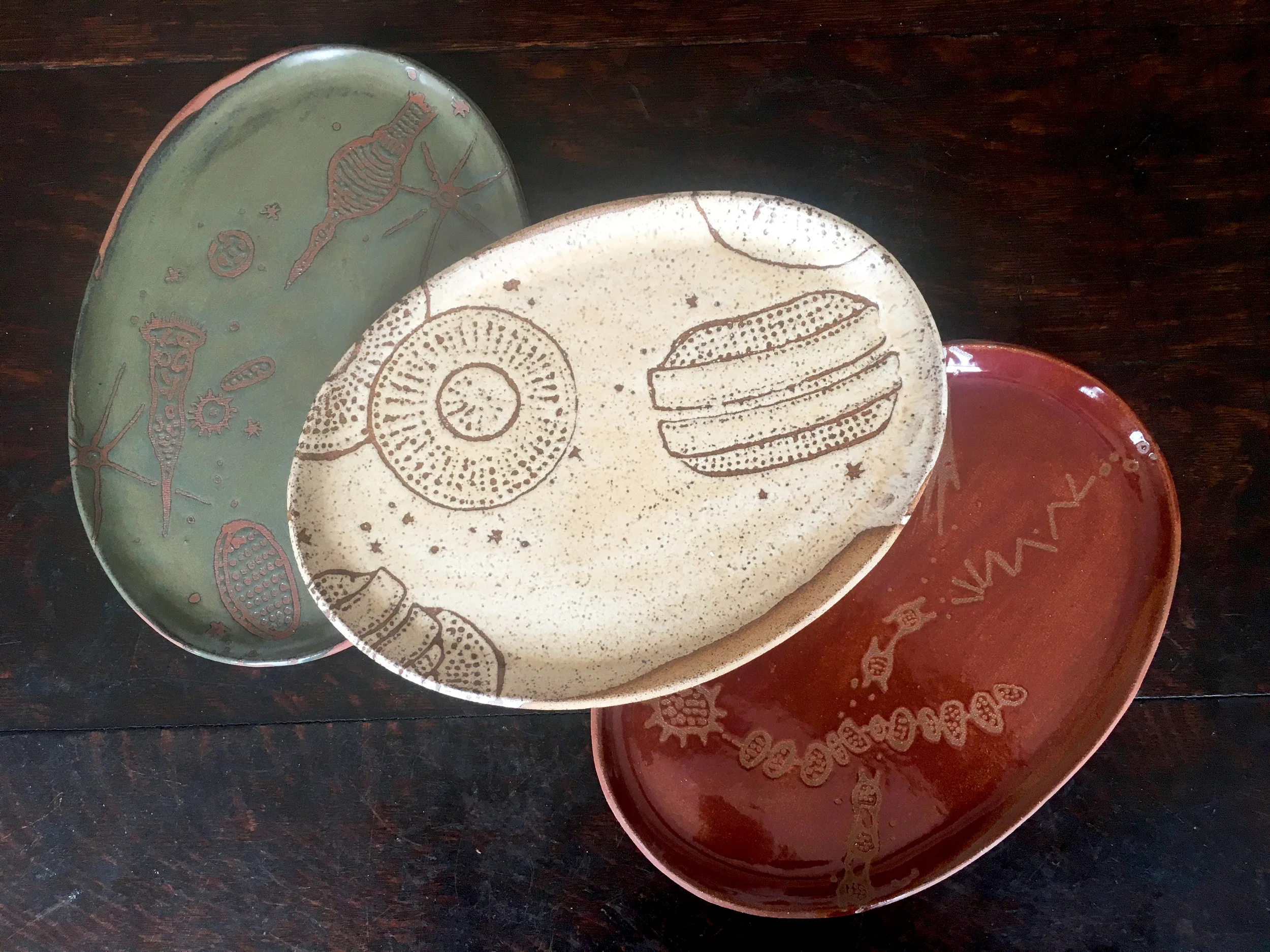 Platters are oval in small, medium & large with a wide rim on the grand platter Trio in moss on red clay, créme brûlée on speckled clay & plum on red clay