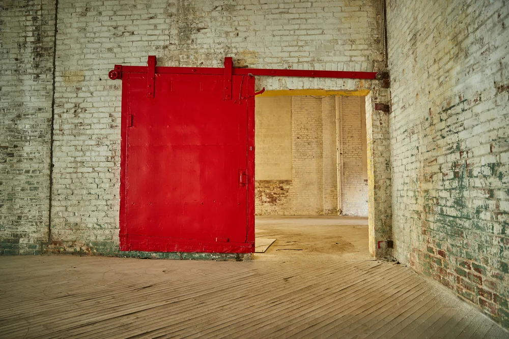 Studio with a red sliding steel door and thick brick walls, used for music rehearsal and recording