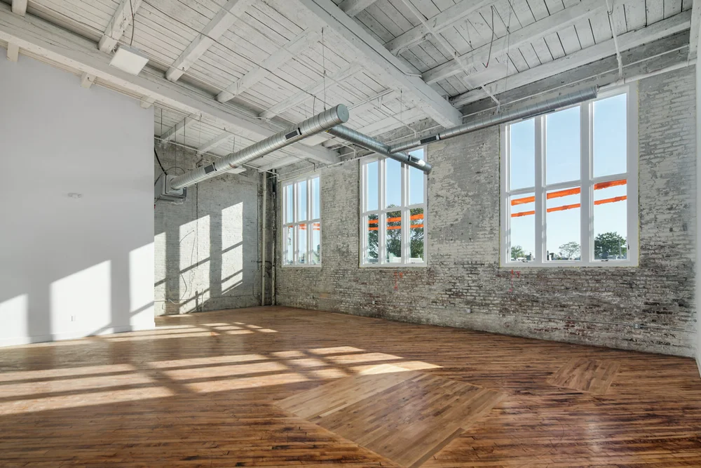 Sunlit studio with tall factory windows and wood floors, suited to photography and video