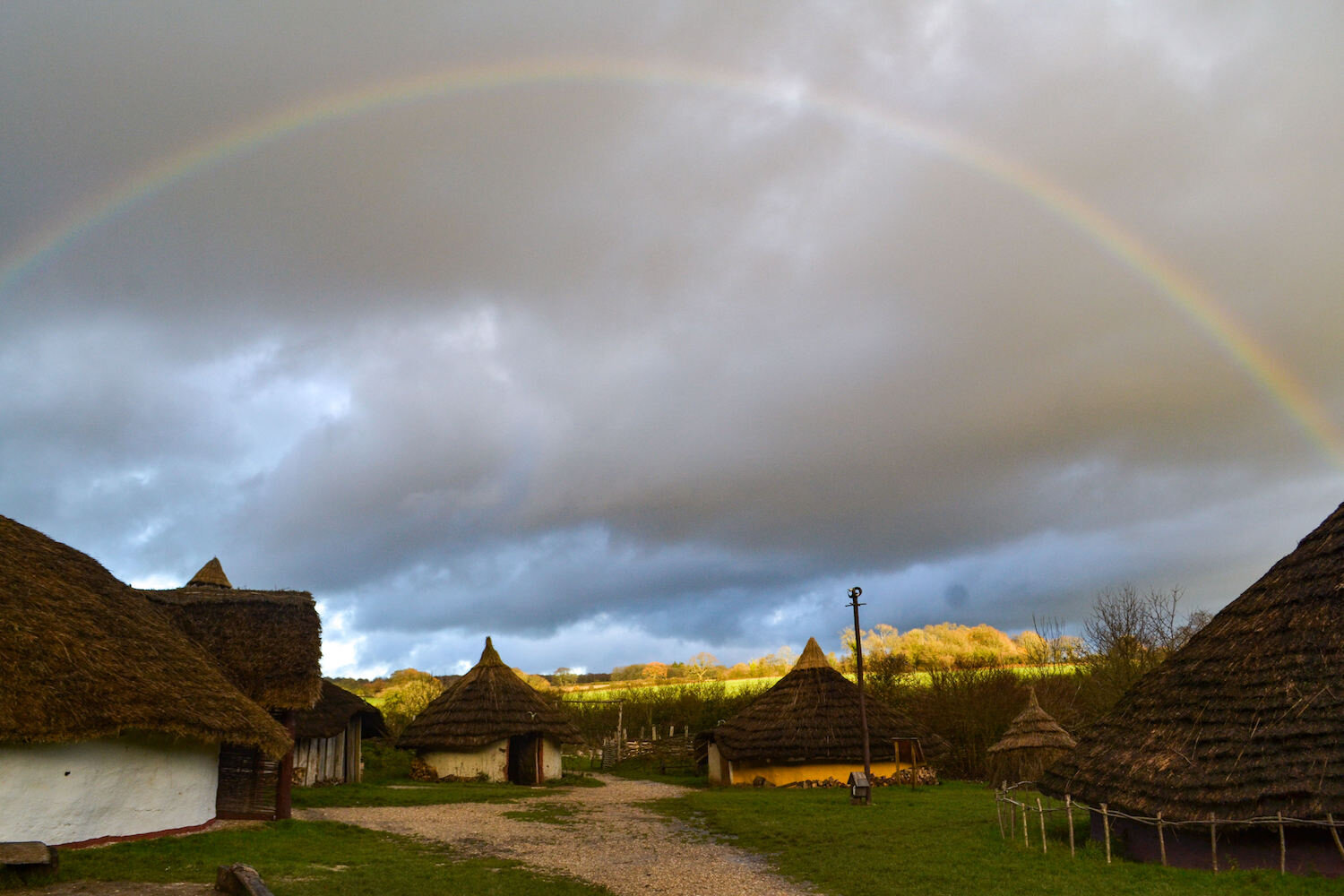 Butser Ancient Farm Iron Age Roundhouse enclosure with rainbow