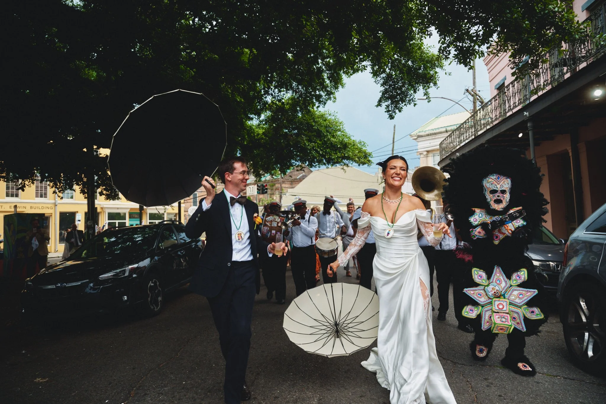  A bride and groom leading their second line down the street with the brass band outside Il Mercato in New Orleans 