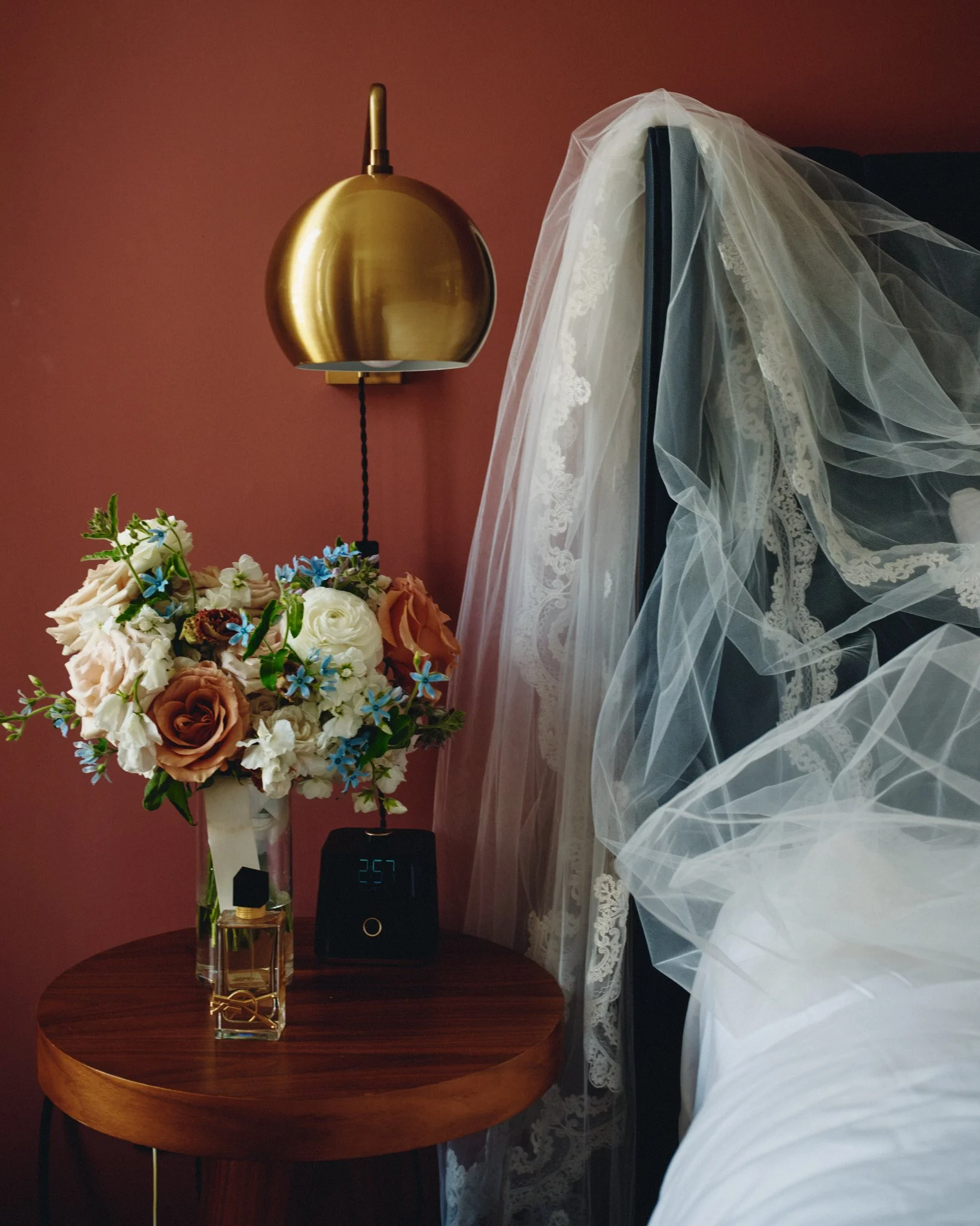  A bridal bouquet and veil set out beside a brass lamp on the wedding morning 