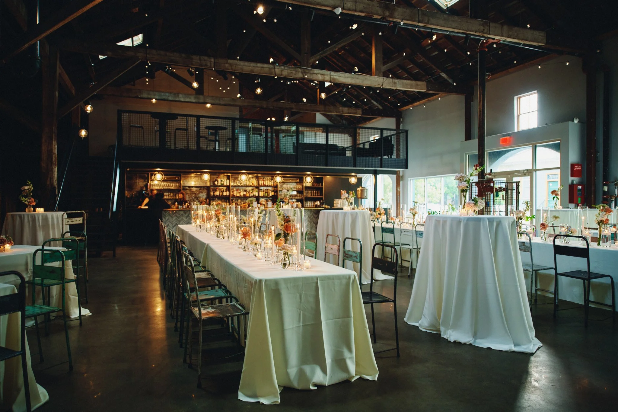  The reception room at Capulet in New Orleans, wooden beams and string lights above long tables 