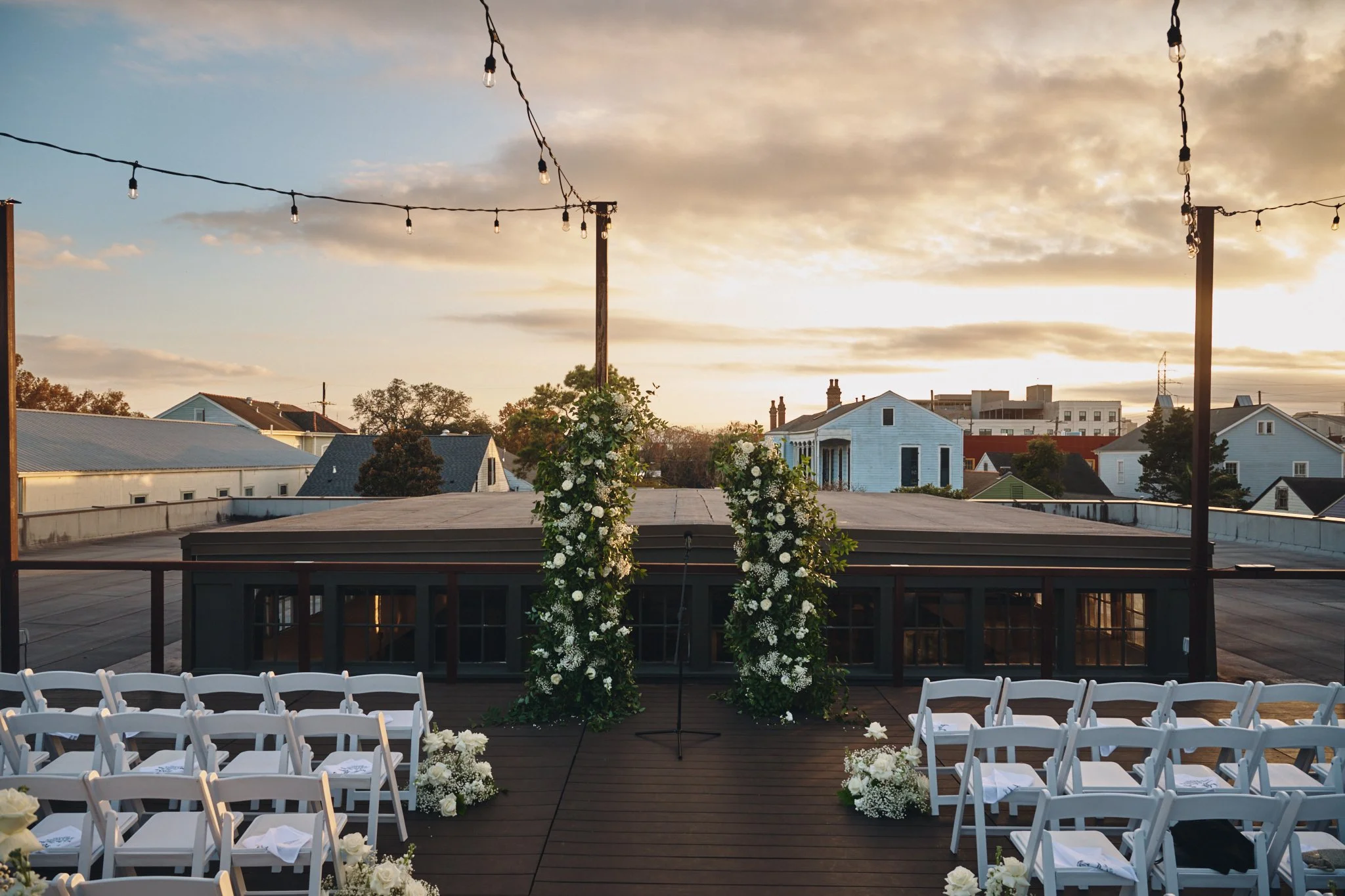  The rooftop ceremony deck set with floral columns and string lights at sunset at Capulet in New Orleans 