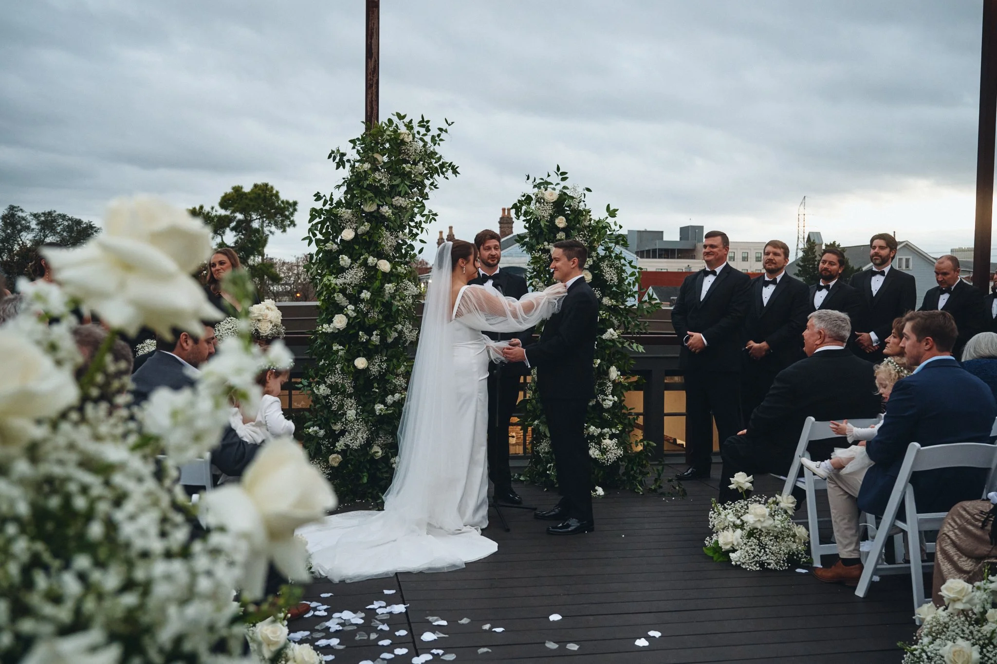 A bride and groom exchanging vows between floral columns on the rooftop at Capulet in New Orleans 