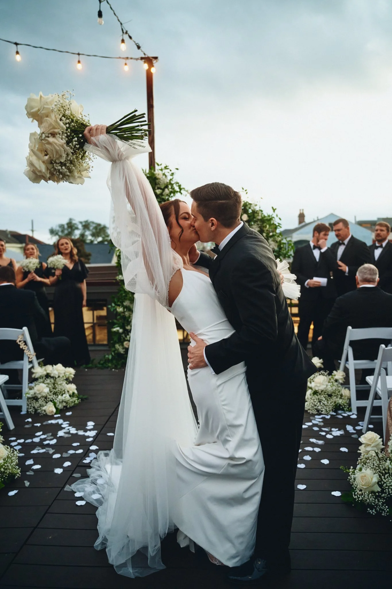  A bride raising her bouquet as she kisses the groom at the end of the ceremony at Capulet in New Orleans 