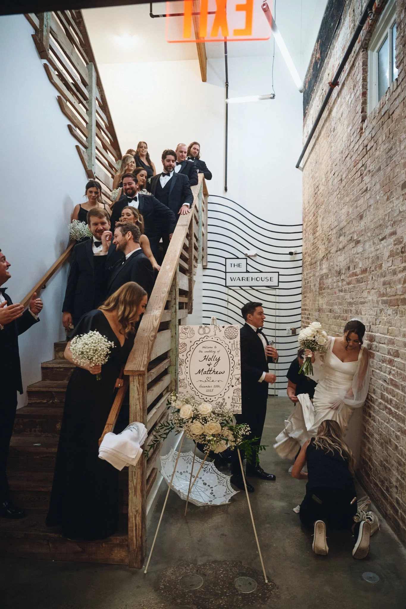  The wedding party waiting on the warehouse stairs beside the welcome sign at Capulet in New Orleans 