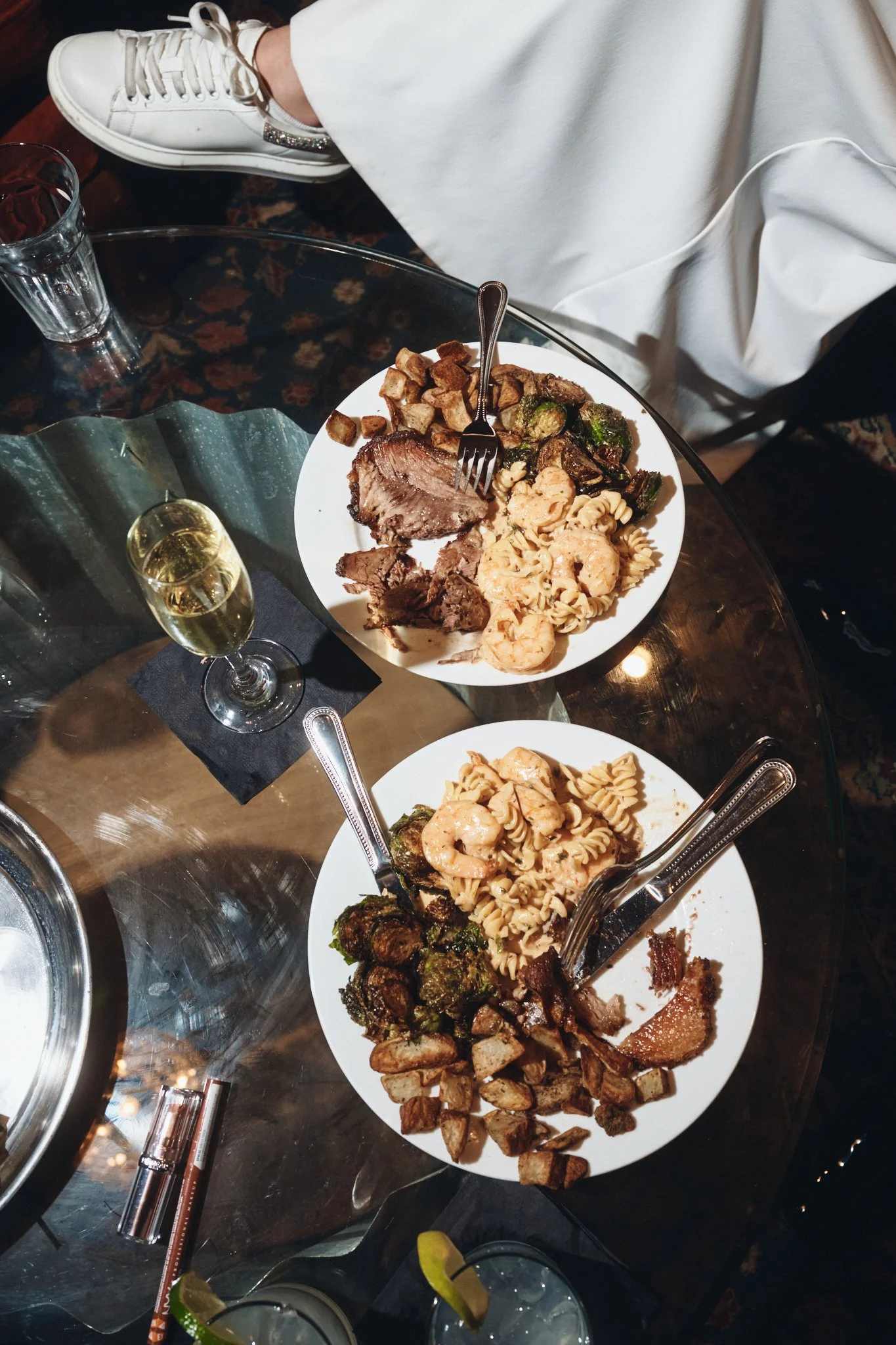  Two plates of New Orleans wedding food and a glass of champagne on a cafe table at Capulet in New Orleans 