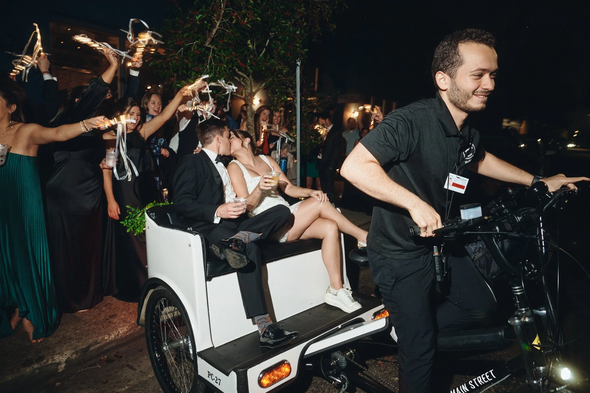  A bride and groom kissing in a pedicab as guests hold sparklers outside Capulet in New Orleans 