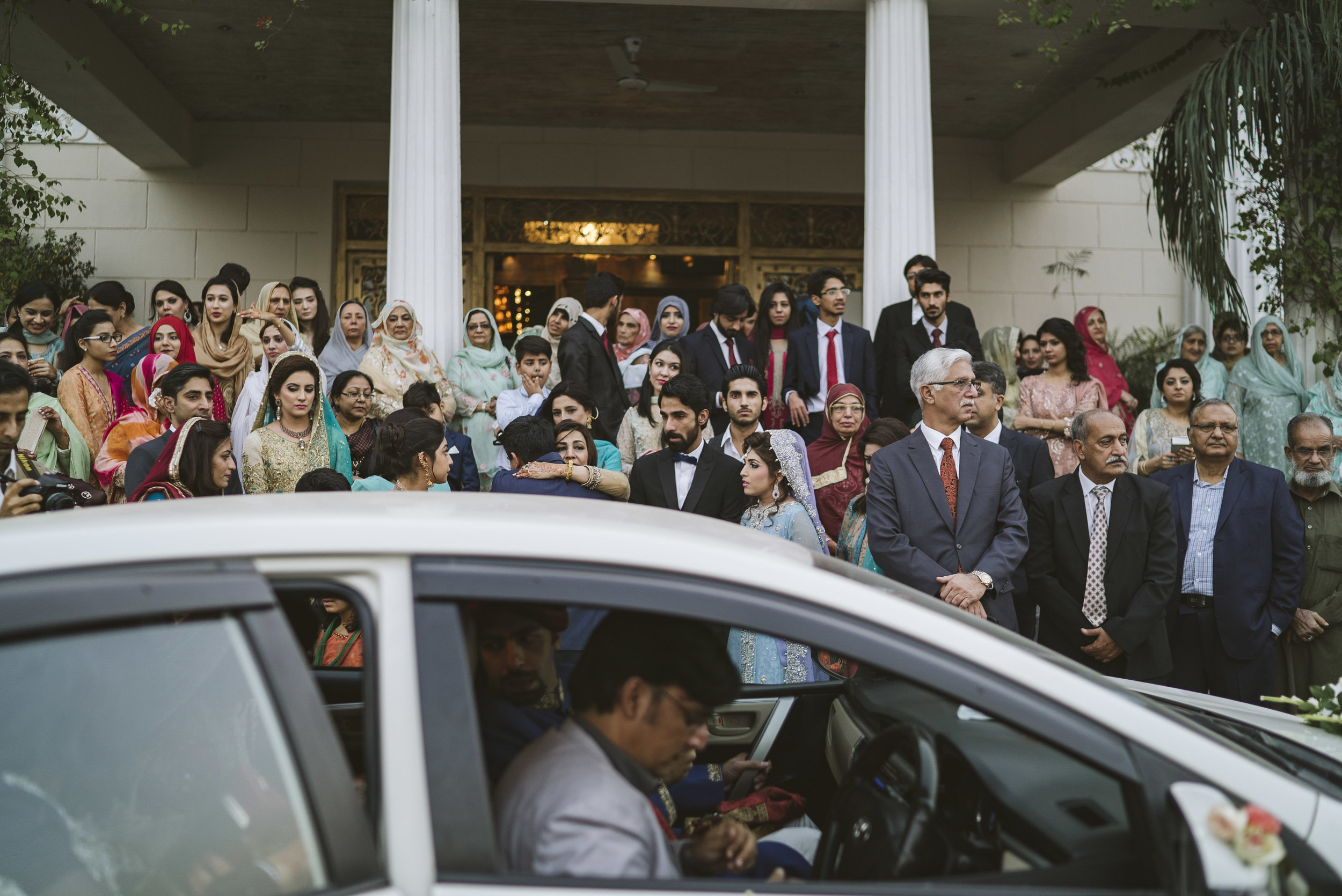  Kashif Malik hugs his new mother-in-law before departing with his new wife, Sadaf, to his family's home on the day of their  baraat . The departing of the bride is usually a somber affair, and Sadaf's family watches on in silence as she and her husb