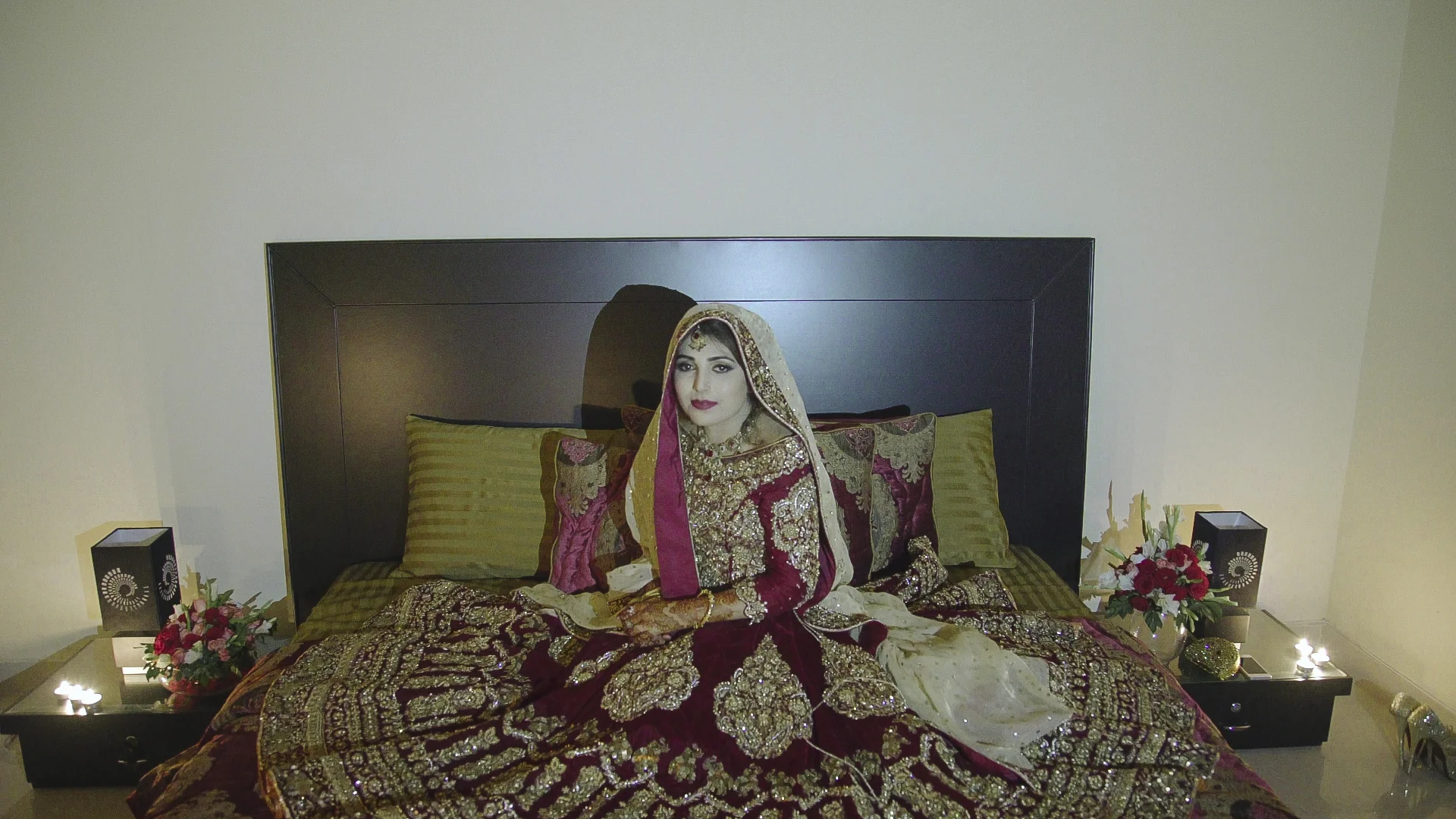 Ayesha Sadal waits for her husband in the candlelight of their bedroom on the night of their baraat . This significant ritual is called suhag raat , which refers to the first night and consummation of the marriage. Traditionally, the female members of the families guide the bride to the decorated bedroom where she waits for her husband's arrival. The bed of the newlywed couple is decorated with rose petals and other flowers, which are believed to bring sweetness to their relationship. On the other side of the door, Ayaz's friends set up camp and block him from coming in - a lighthearted tradition that results in him acquiescing to demands for hours and "paying up" before finally being let into the bedroom.