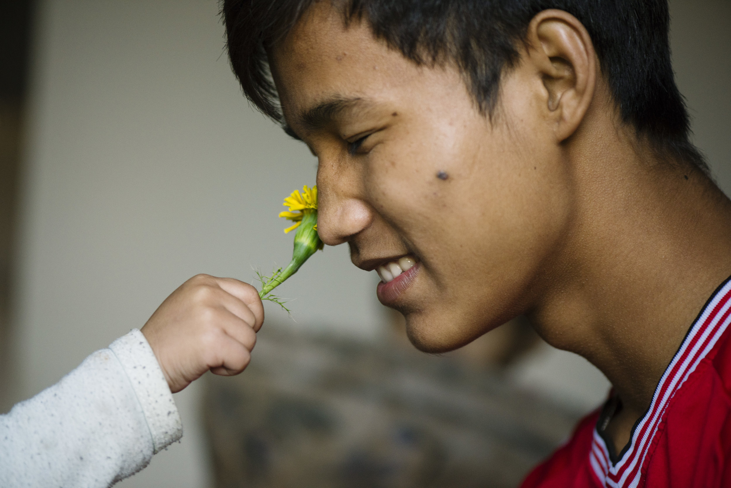  The youngest daughter in the family, Nga Meh, 2, puts a flower up to her brother Soe Reh's nose and asks him to smell it. He obliges, tucking it behind his ear. 