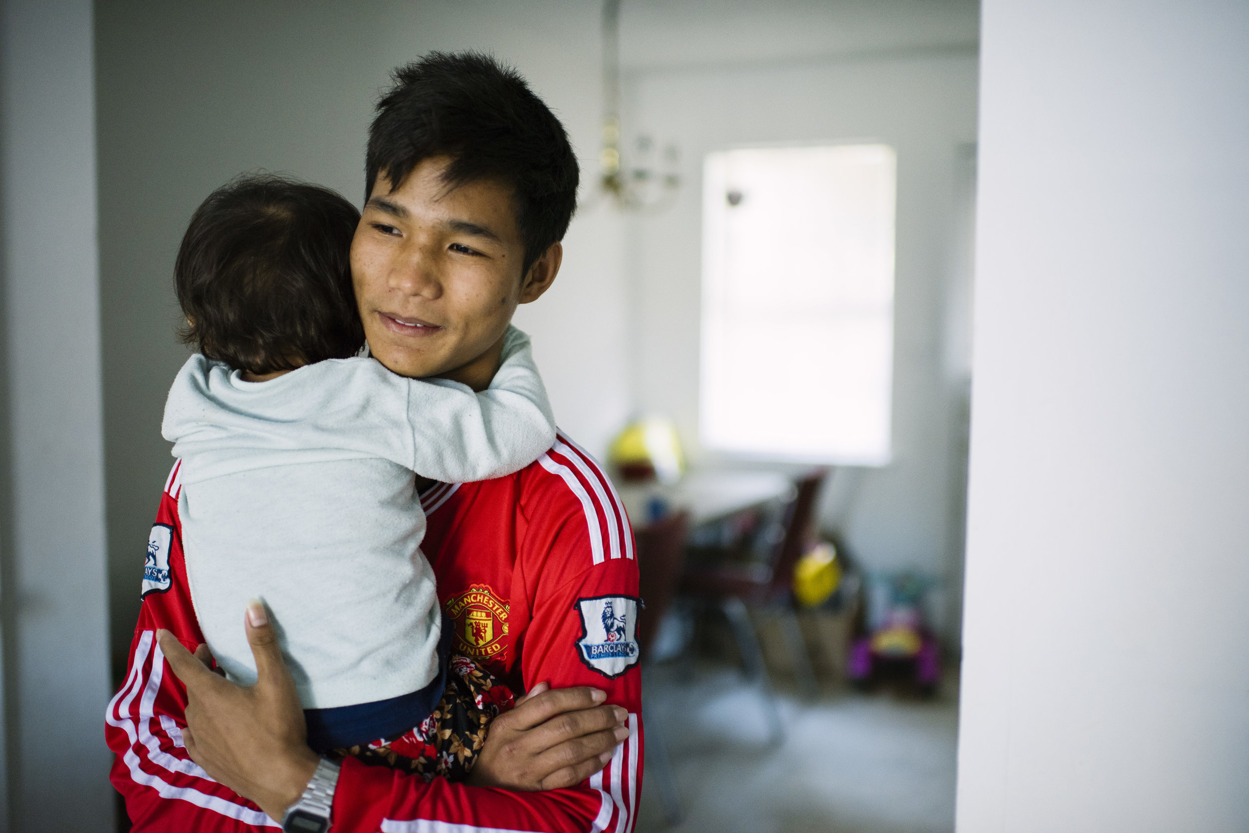  Soe Reh, 19, holds his youngest sister, Nga Meh, 2, at their apartment after she started crying. 