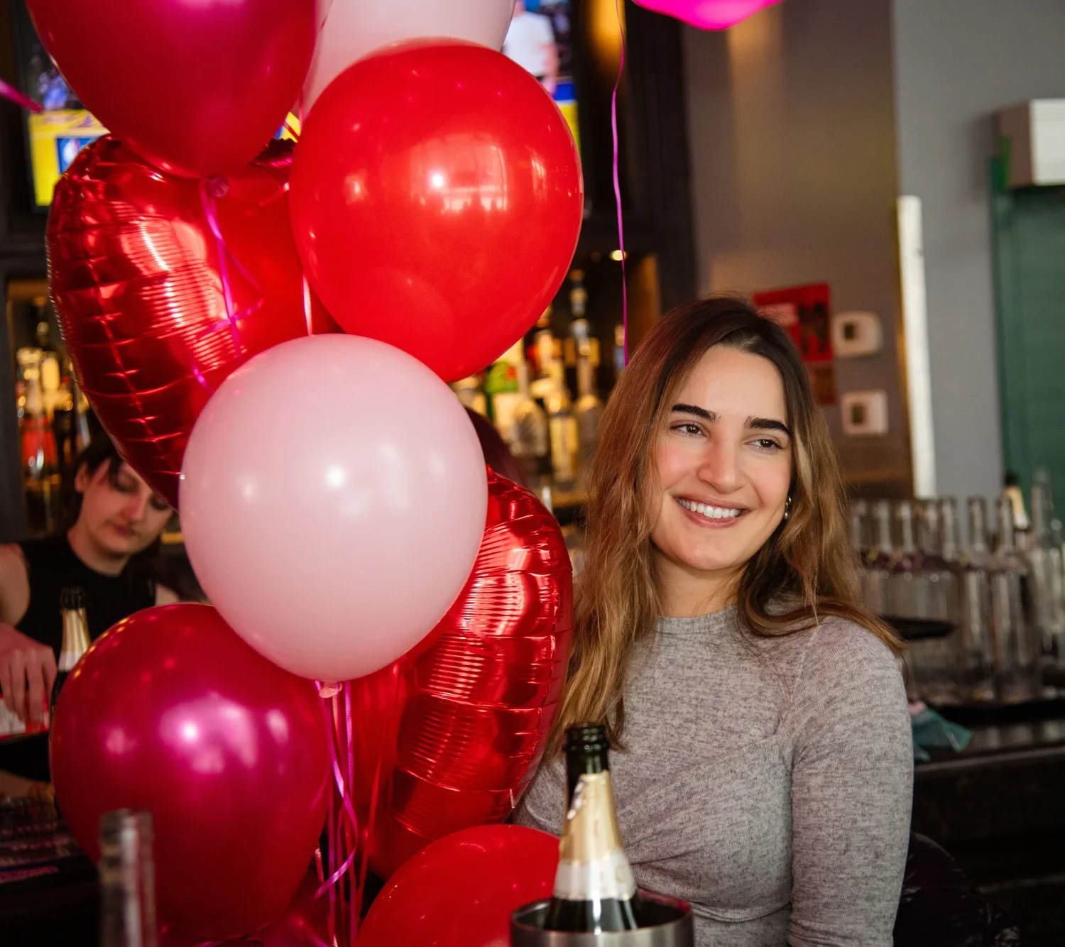 Woman smiling beside red and pink balloons during a celebration at Fox On John.