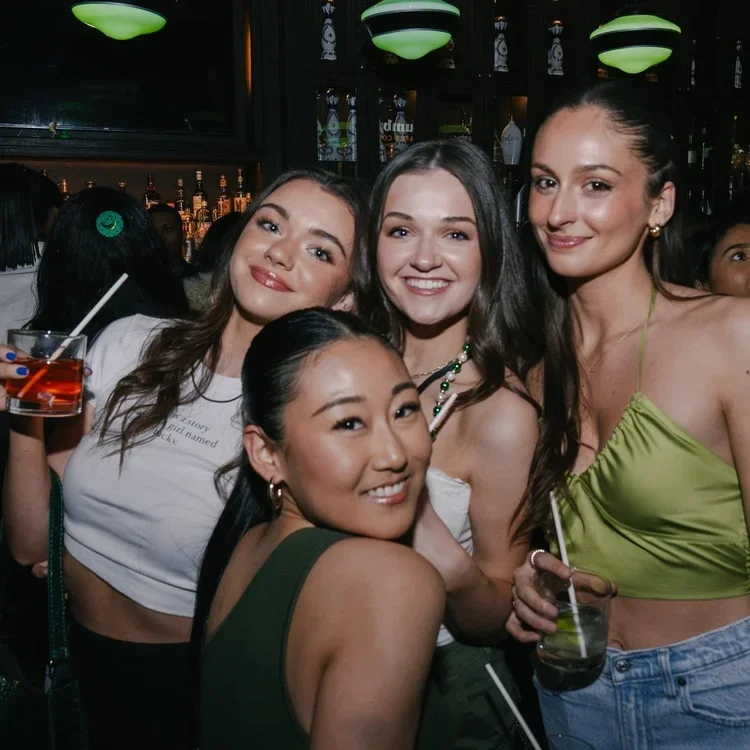 Friends smiling and holding cocktails at Fox on John, enjoying a lively bottomless brunch in Toronto’s Entertainment District.