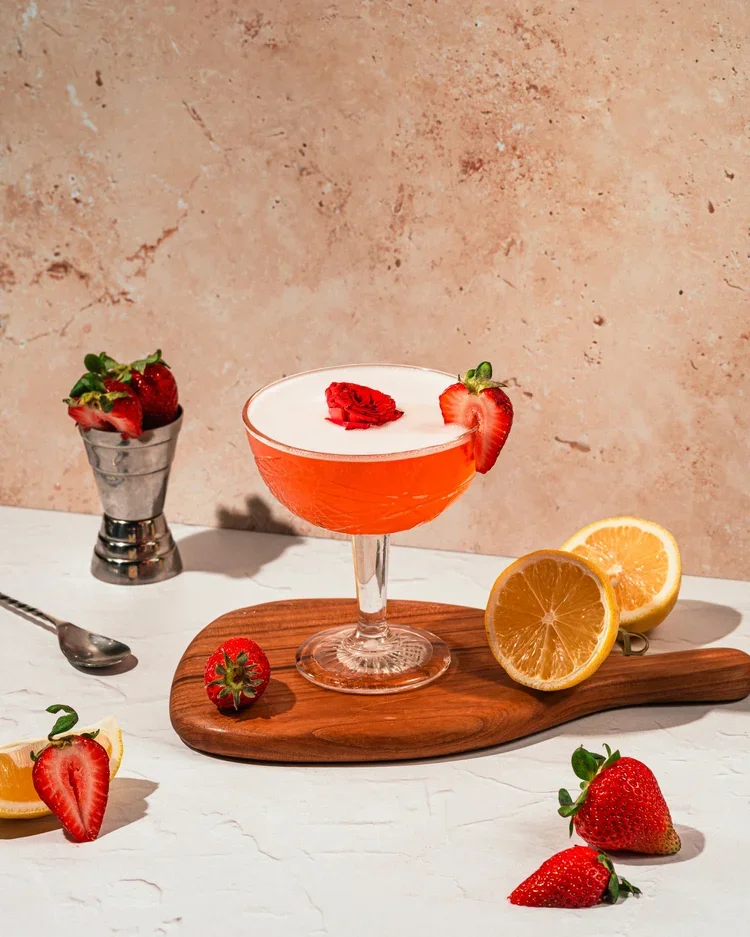 Strawberry cocktail with citrus garnish served on a wooden board at the Fox on John bar.