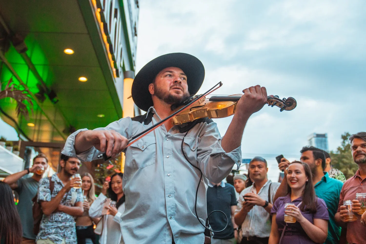 Fox on John, outdoor live music with a violinist, as a crowd gathers with drinks.