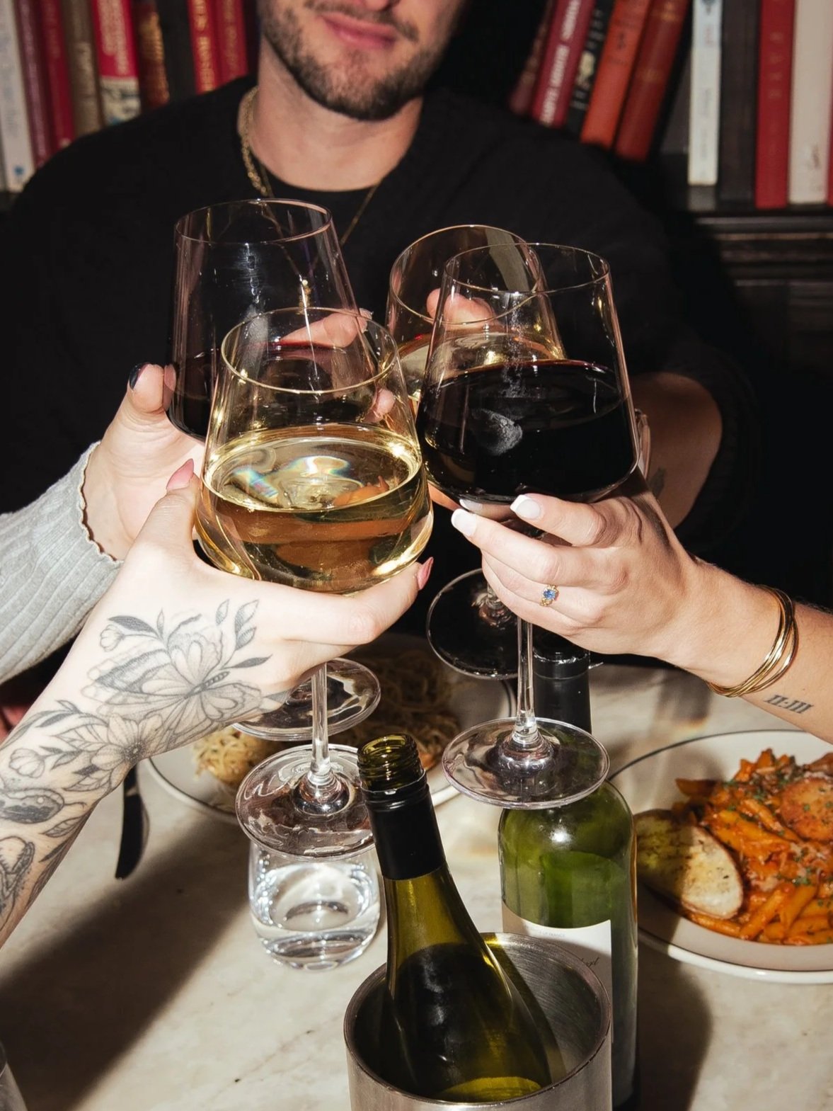 A glass of white wine on a wooden surface next to a wine bottle.