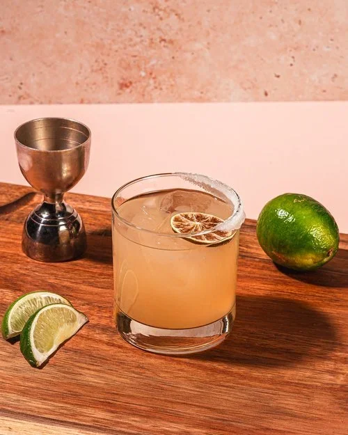 Signature margaritas from Fox on John served with lemons on a wooden table.