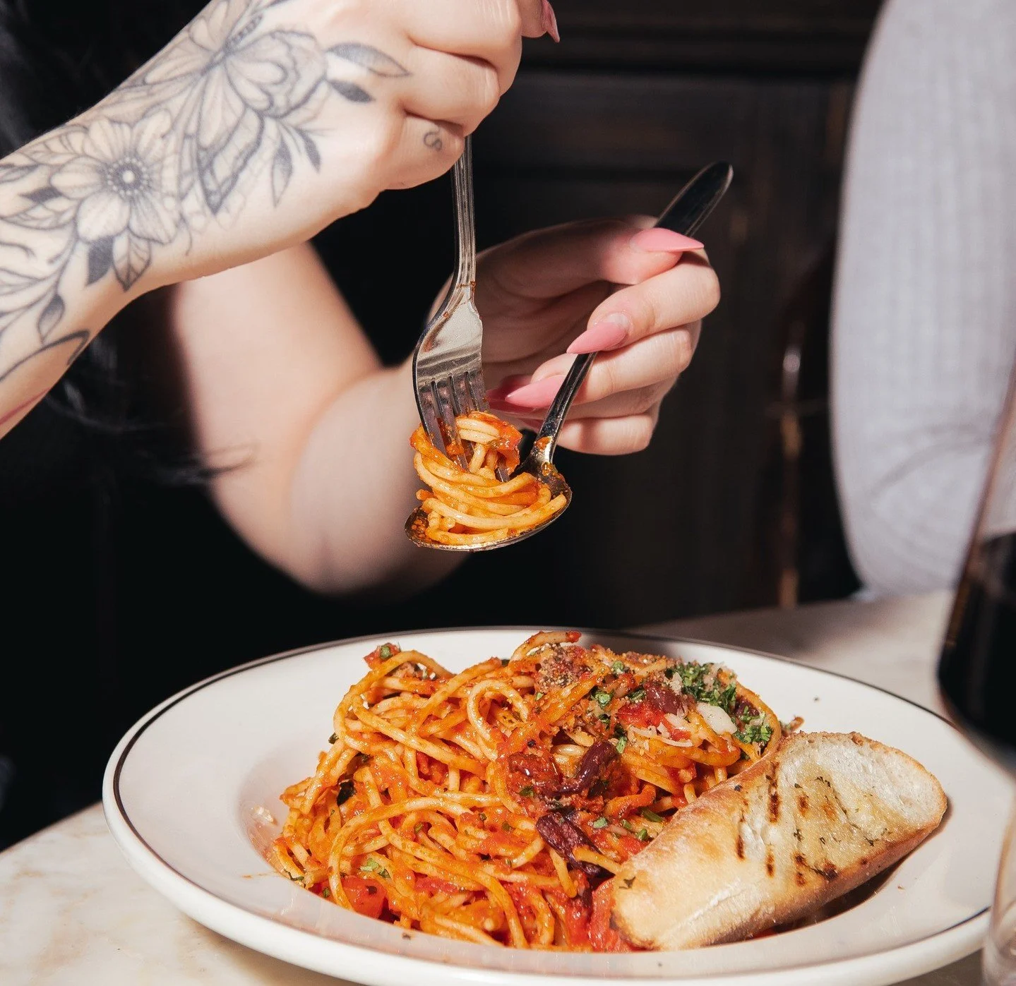 Fox on John's pasta dish with fork-twirled spaghetti in rich tomato sauce, served with toasted bread.