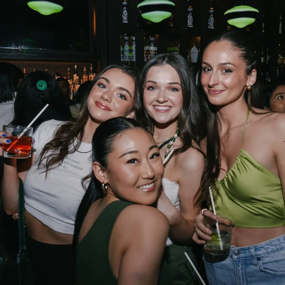 Friends posing with cocktails and smiles during a lively night out at Fox on John.