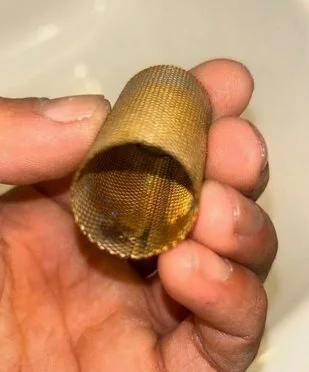 Heating engineer holding a cleaned strainer