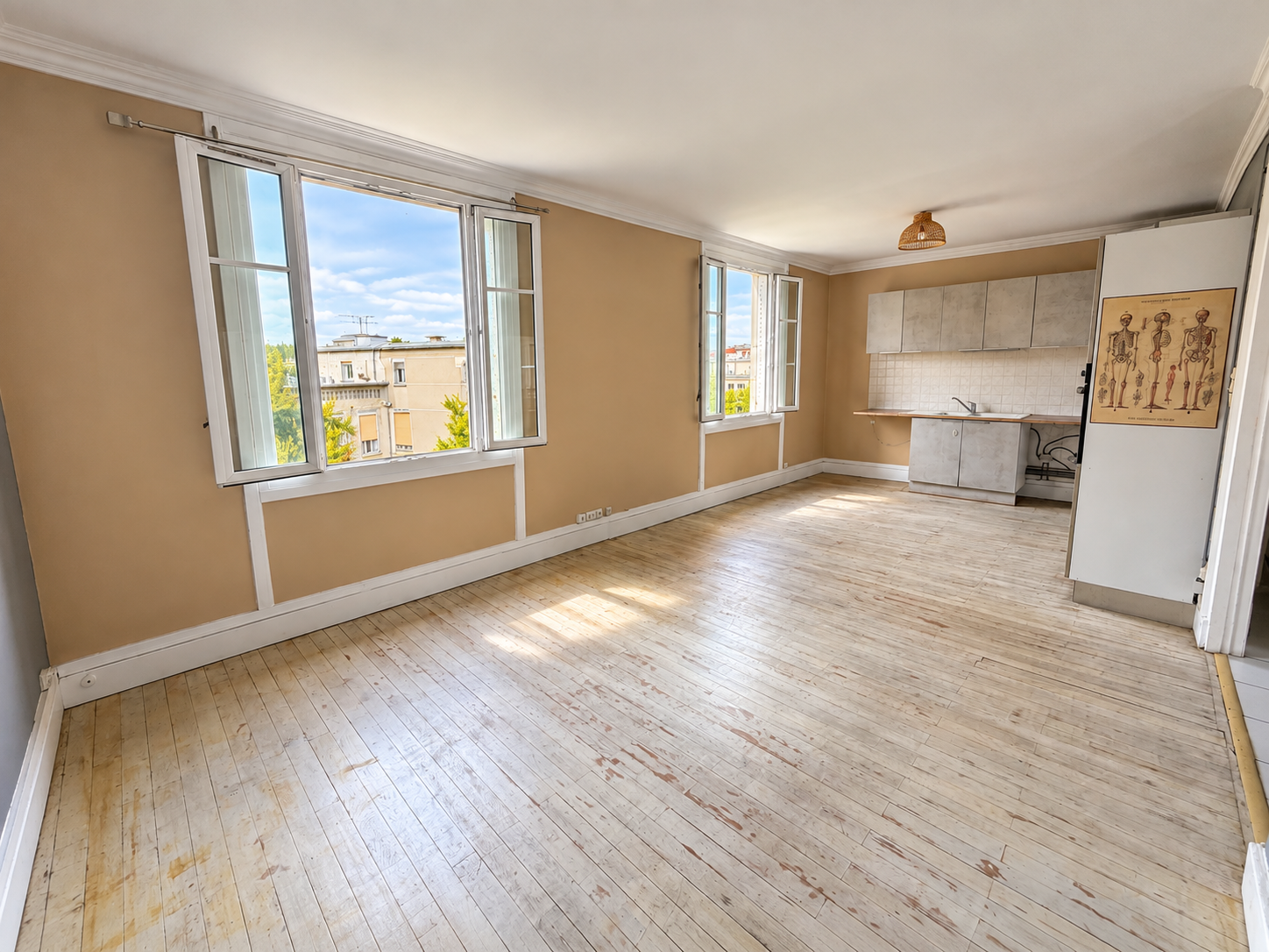 Salon vide lumineux avec kitchenette et fenêtres ouvertes.png
