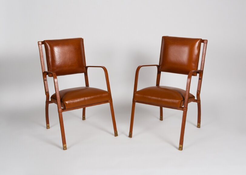 Armchairs, saddle-stitched leather and brass (c. 1950) by Jacques Adnet, image c/o Maison Gerard