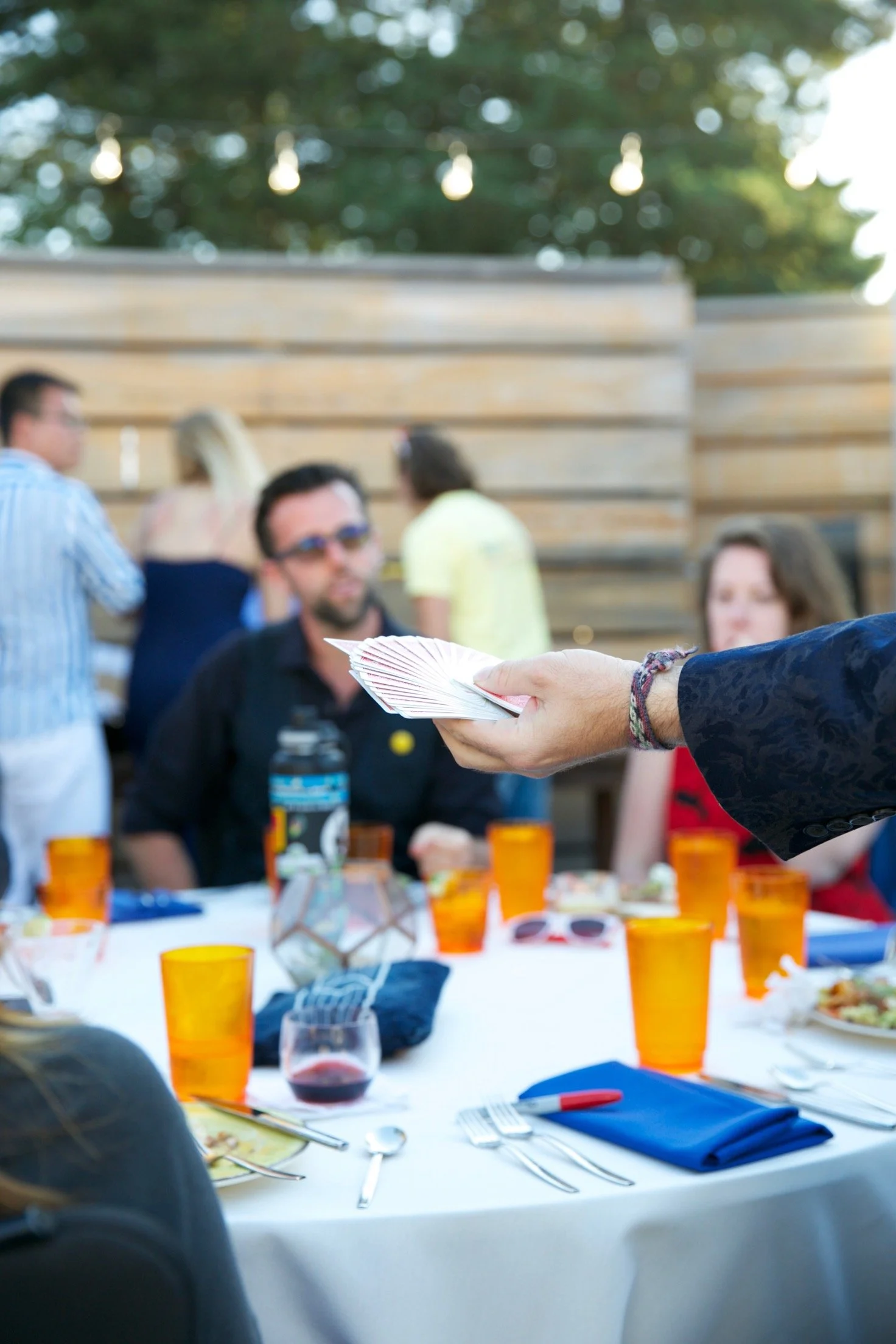 Magician Joshua Logan fanning a deck of cards for guests at an outdoor event table
