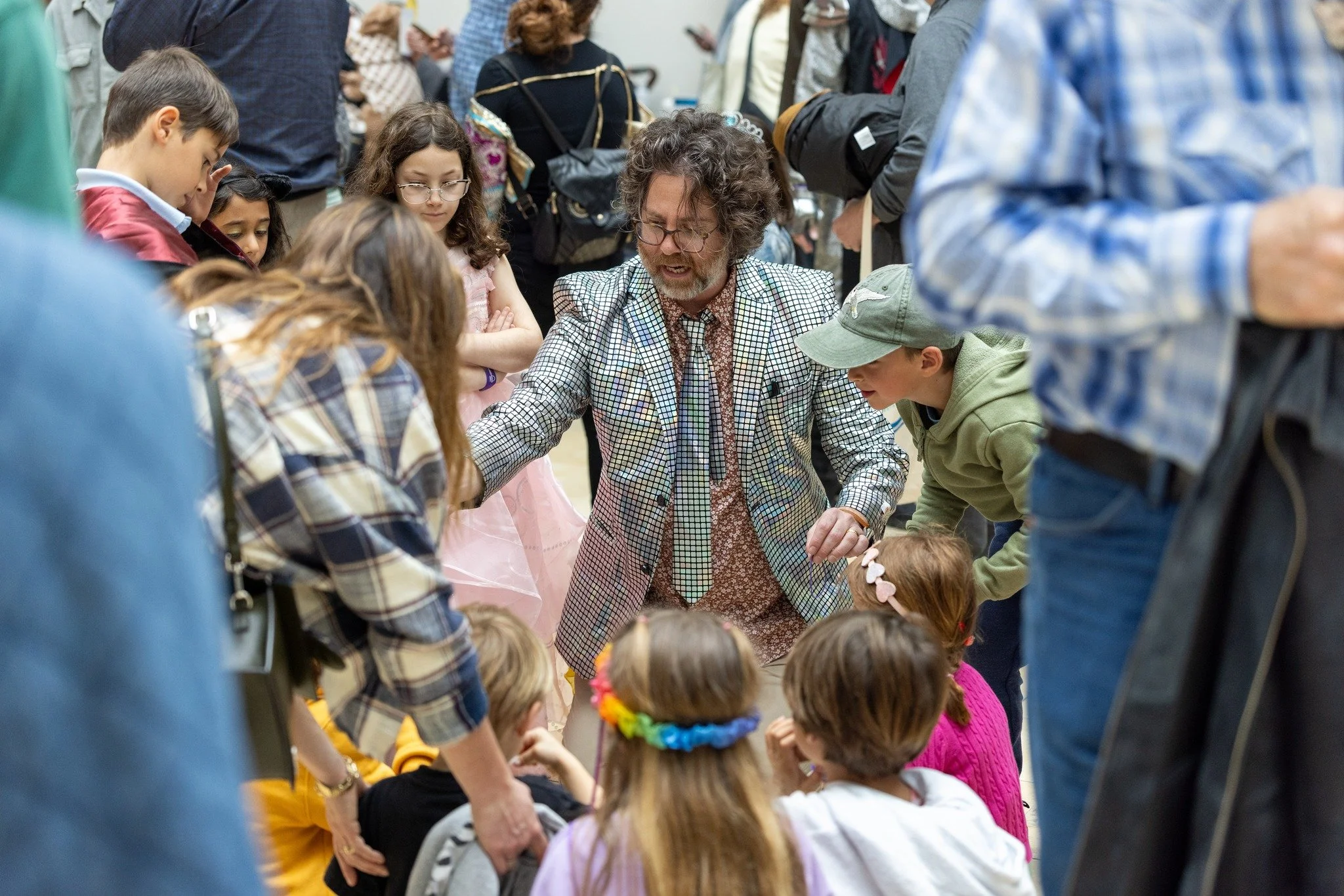 Joshua Logan performing close-up magic for a crowd of excited kids and families in San Francisco