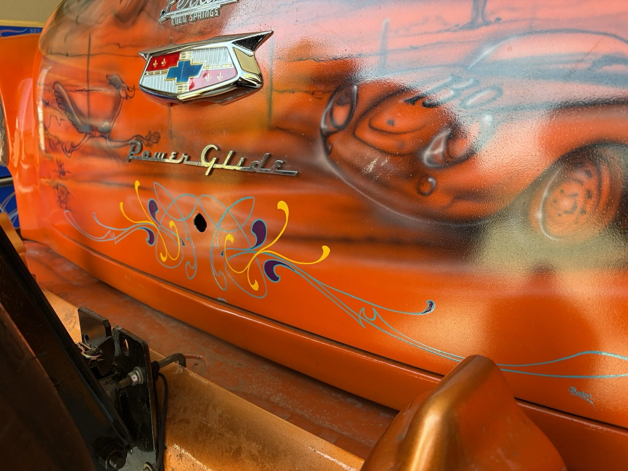 Orange lowrider trunk lid with turquoise, purple, and chrome yellow pinstriping by Matt Beckner.