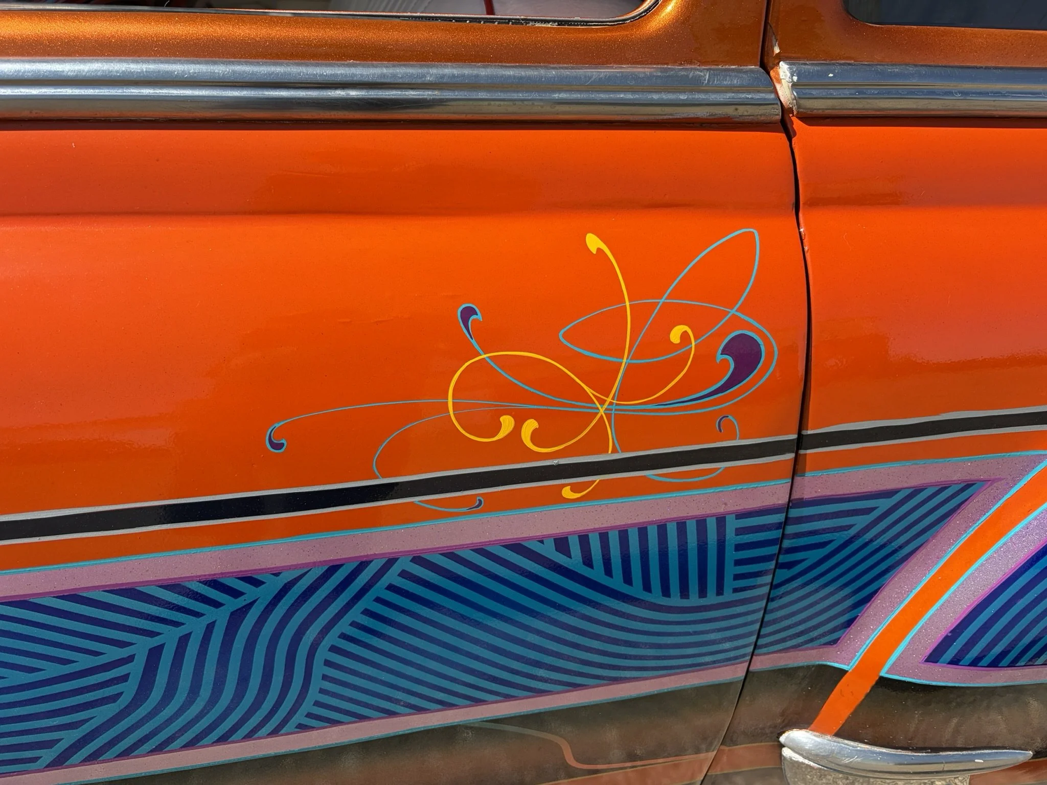 Orange lowrider door with turquoise, purple, and chrome yellow pinstriping by Matt Beckner.